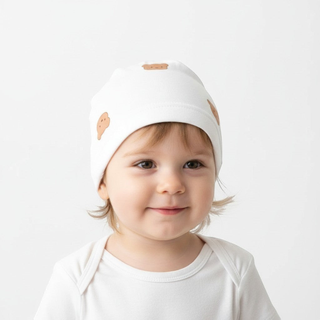 Peek Ah Boo white cotton infant beanie with all-over brown teddy bear print. Soft, hypoallergenic, and breathable.