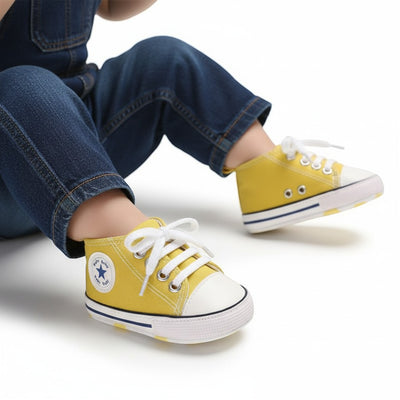 Peek Ah Boo yellow canvas toddler shoes with white laces and a blue star logo, designed for first walkers with anti-slip soles.